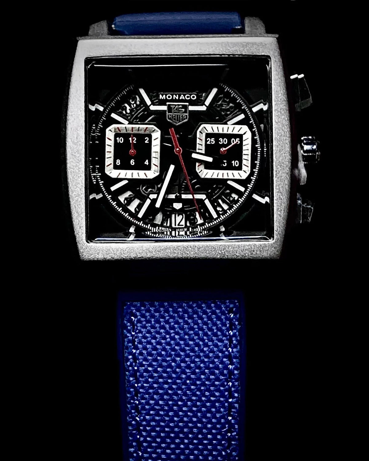 Watch with blue strap and detailed face on a black background