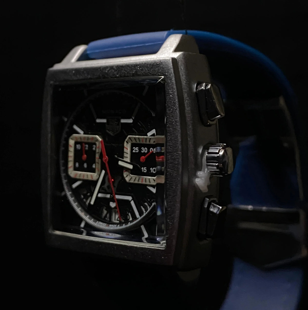 Close-up of a detailed wristwatch with a blue strap on a dark background