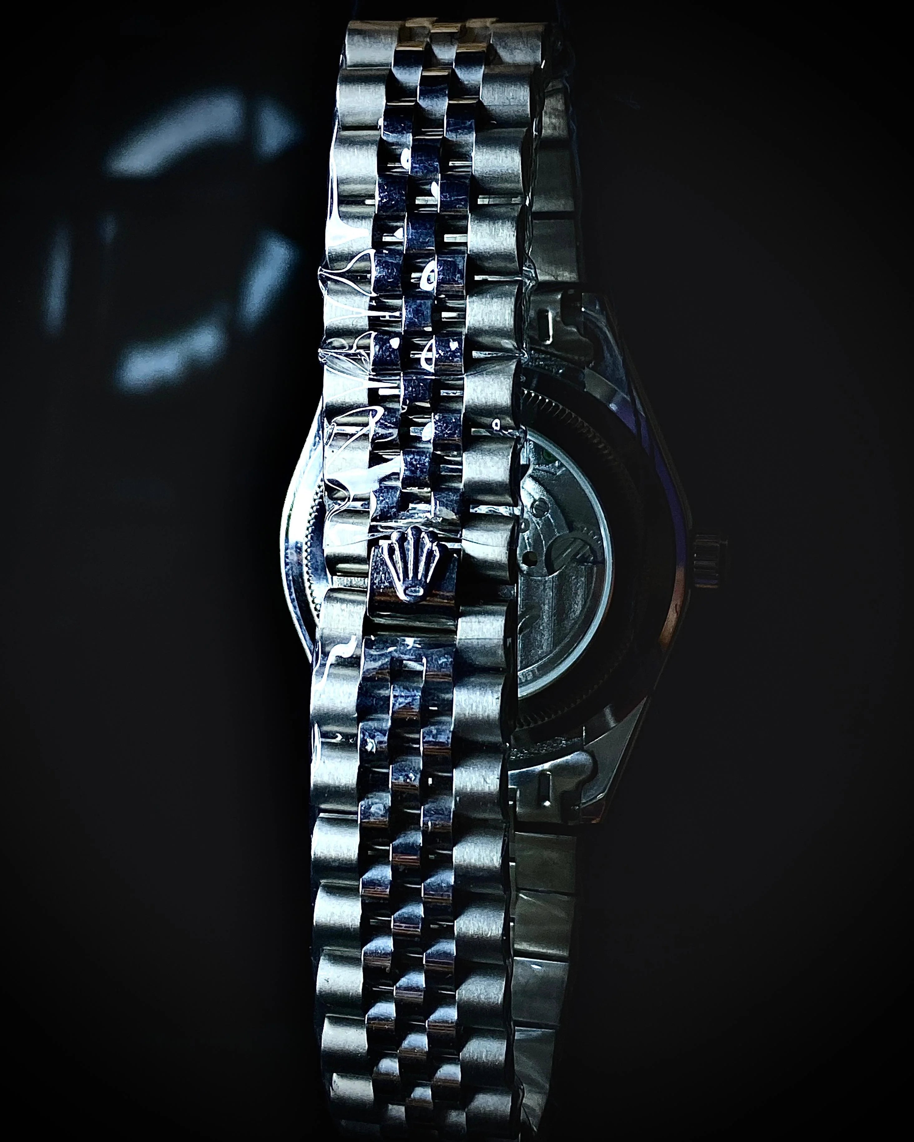 Close-up of a silver watch with a dark background